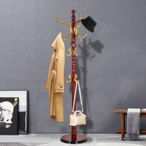 A wooden coat rack with gold hooks stands against a gray wall. A beige trench coat, a black hat, and a white handbag are hanging from the rack.