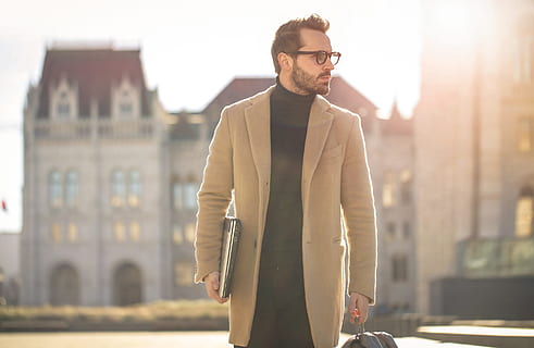 A person wearing a beige trench coat over jeans and sneakers for a relaxed street-style look.